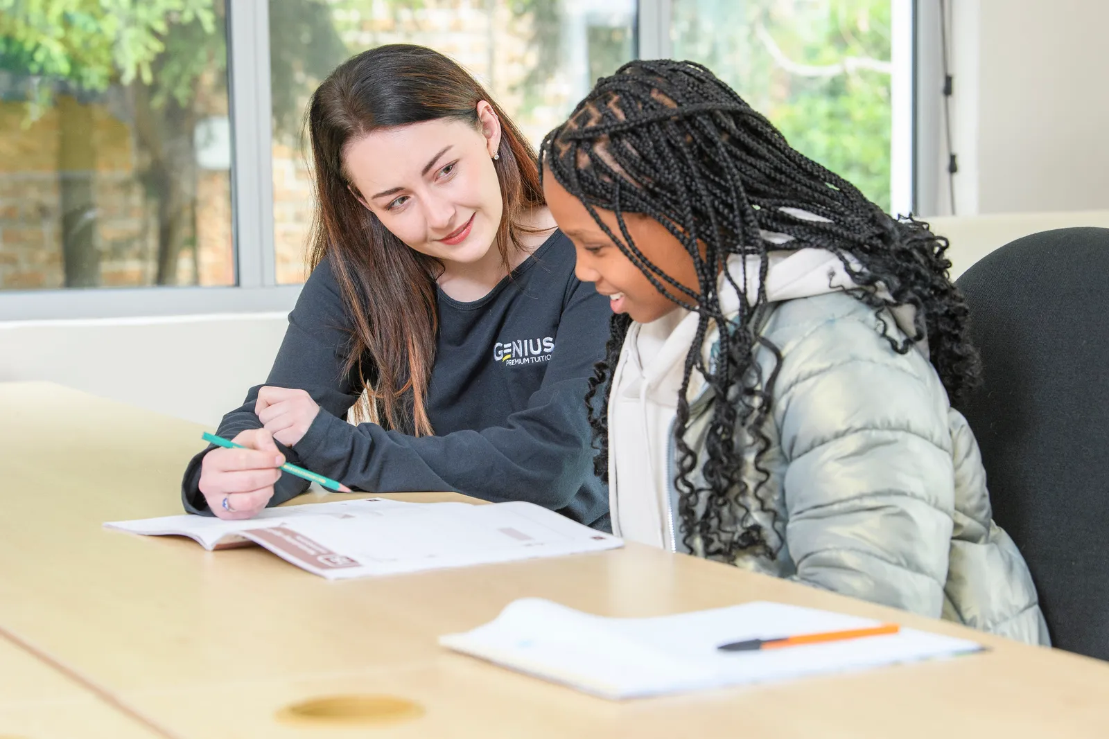 A Genius tutor supporting a student during a one-on-one lesson at a table