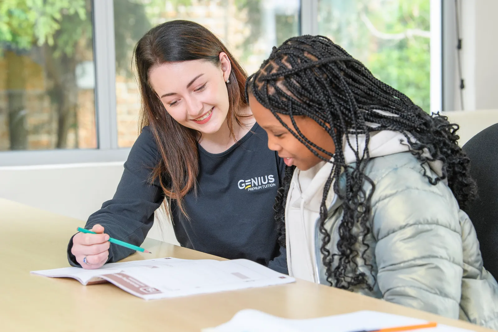 A Genius tutor and an older student working through an open workbook together